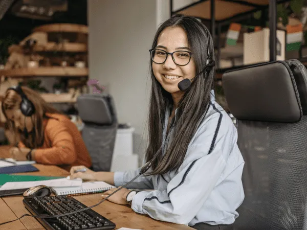 a woman wearing a headset and sitting at a desk helping with customer support