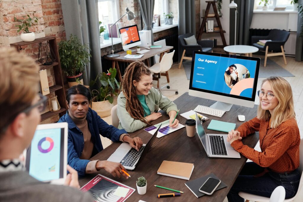 a group of people from an agency sitting around a table with computers doing multi-client management.